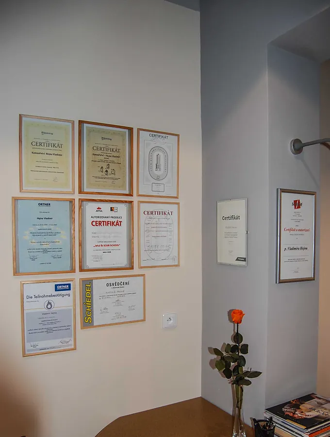 Rámované certifikáty a osvědčení na stěně krbového studia